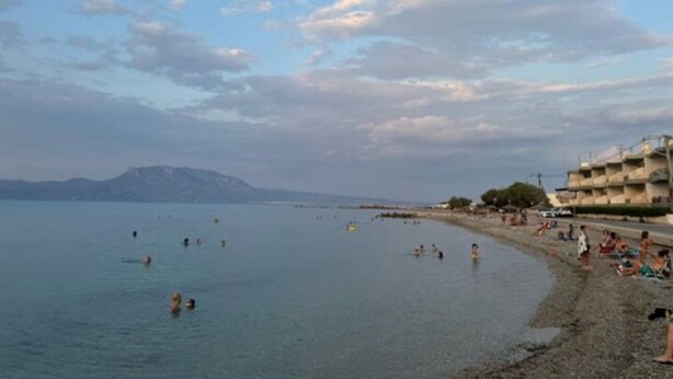 Une plage où l’on peut se baigner et se détendre, un ciel dégagé et des montagnes à l’horizon.