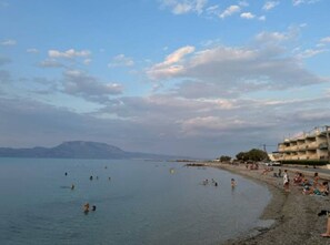 Une plage où l’on peut se baigner et se détendre, un ciel dégagé et des montagnes à l’horizon.
