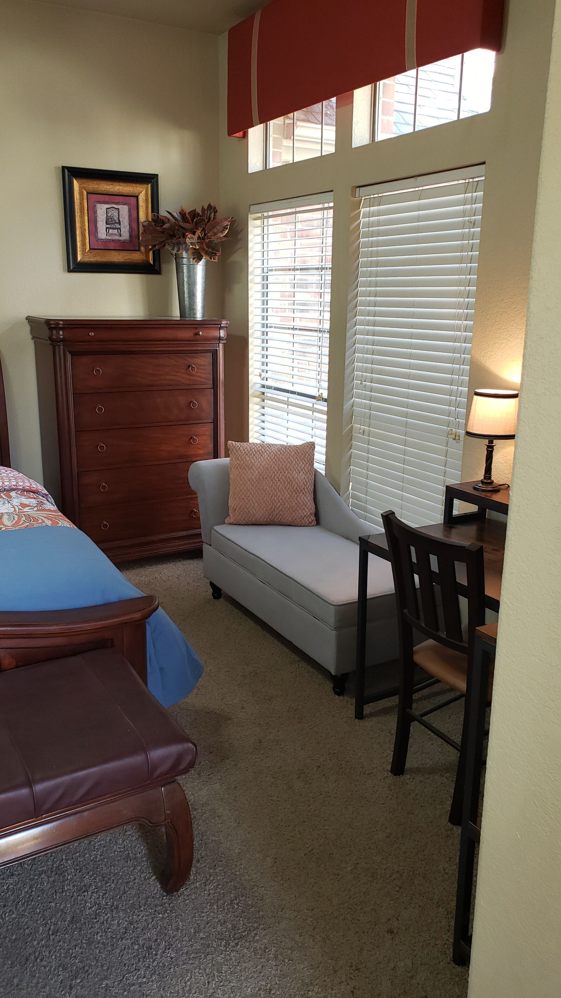 A bedroom with a bed, a dresser, a chair, and a desk.