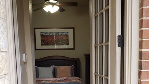 A bedroom with a bed, a ceiling fan, and a framed picture on the wall.