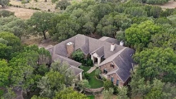 An aerial view of a house surrounded by dense trees.