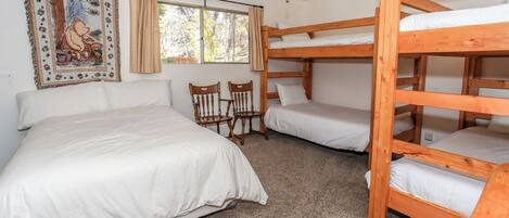 Una habitación con literas, una cama individual, ventilador de techo y ventana con cortinas.