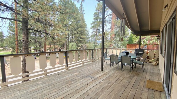A wooden deck with a table and chairs, surrounded by trees.