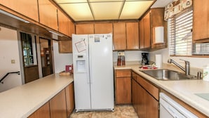A compact kitchen with wooden cabinets, a white refrigerator, a dishwasher, and a sink.