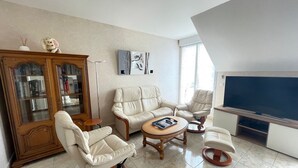 A living room with a sofa set, a television, a cabinet, and a floor lamp. - Spacious apartment for 6 people with balcony, Sarzeau (Sarzeau)