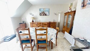 A dining area with a round table, wooden chairs, a cabinet, and a painting on the wall. - Spacious apartment for 6 people with balcony, Sarzeau (Sarzeau)