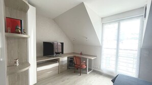A bedroom with a sloped ceiling, a desk with a computer, a chair, and a bed. - Spacious apartment for 6 people with balcony, Sarzeau (Sarzeau)