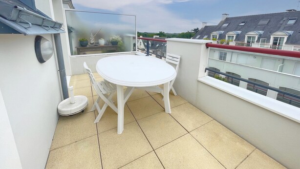 A small outdoor balcony with a white table and chairs, a potted plant, and a view of neighboring buildings. - Spacious apartment for 6 people with balcony, Sarzeau (Sarzeau)