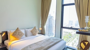 A hotel room with a large bed, two bedside lamps, a nightstand, a window with curtains, and a view of buildings. - Binghatti Gardenia High Floor Olympic  (Dubai)