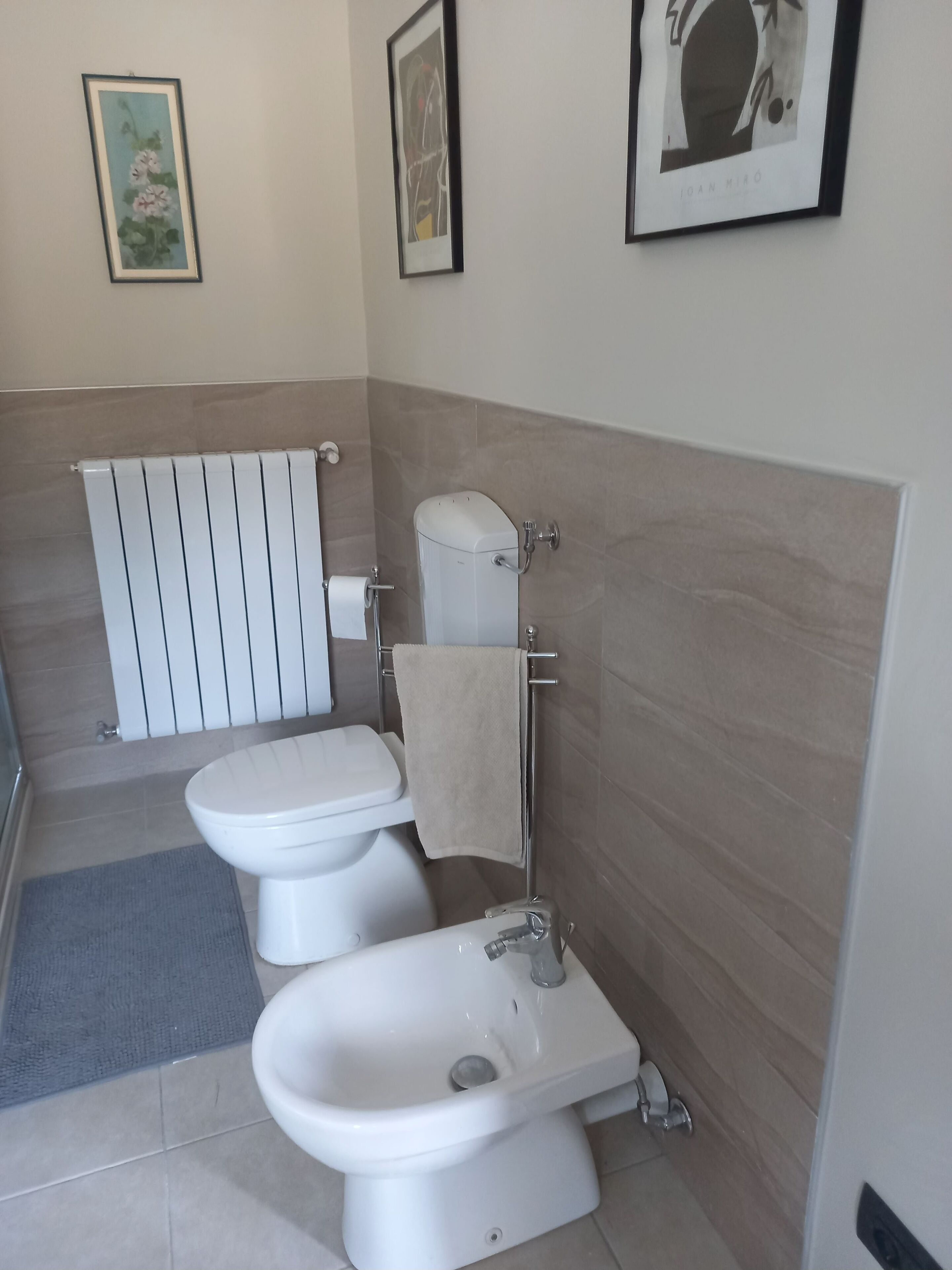 Une salle de bain moderne avec des toilettes, un bidet et une serviette accrochée au mur.
