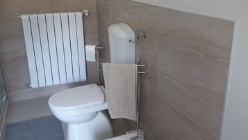 Une salle de bain moderne avec des toilettes, un bidet et une serviette accrochée au mur.