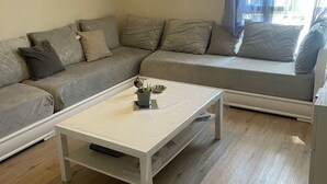A living room with a sofa, a coffee table, and a window with curtains. - Festival apartment (Avignon)