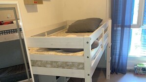 A bunk bed with a desk underneath, a small shelf with decorative items, and a window with curtains. - Festival apartment (Avignon)