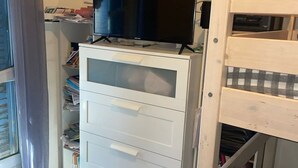 A room with a white desk, a black television on top, and a wooden bunk bed to the right. - Festival apartment (Avignon)