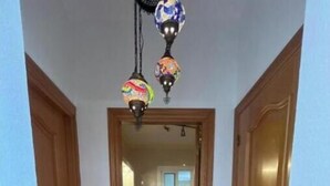 Un couloir doté d’un sol à carreaux, de portes en bois et d’une vue sur une salle de bain avec un lavabo et un miroir.