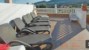 Une terrasse avec plusieurs rangées de chaises longues donnant sur un paysage montagneux.