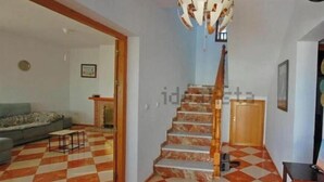 Un escalier dont les marches sont recouvertes d’un carrelage à motifs, menant à un palier, une porte en bois et une horloge au mur.