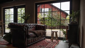 A leather sofa with a throw blanket, a red patterned rug, and a potted plant.