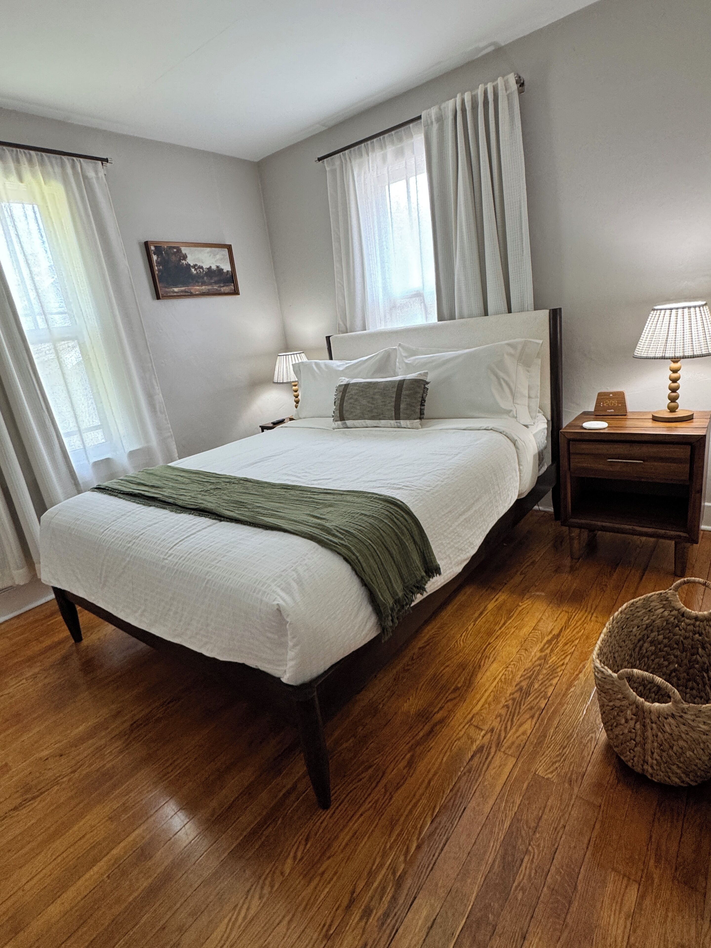 Ein Schlafzimmer mit Bett, Nachttisch, Lampe und einem Korb.