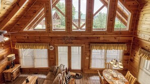 A wooden cabin interior with a dining area, a sofa, and a bench.