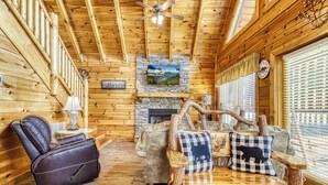 A cozy log cabin interior with a fireplace, a reclining chair, and a wooden coffee table.