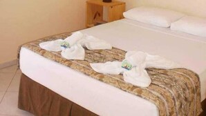 Une chambre d’hôtel avec un lit, des rideaux, une table de chevet et un appareil de climatisation.