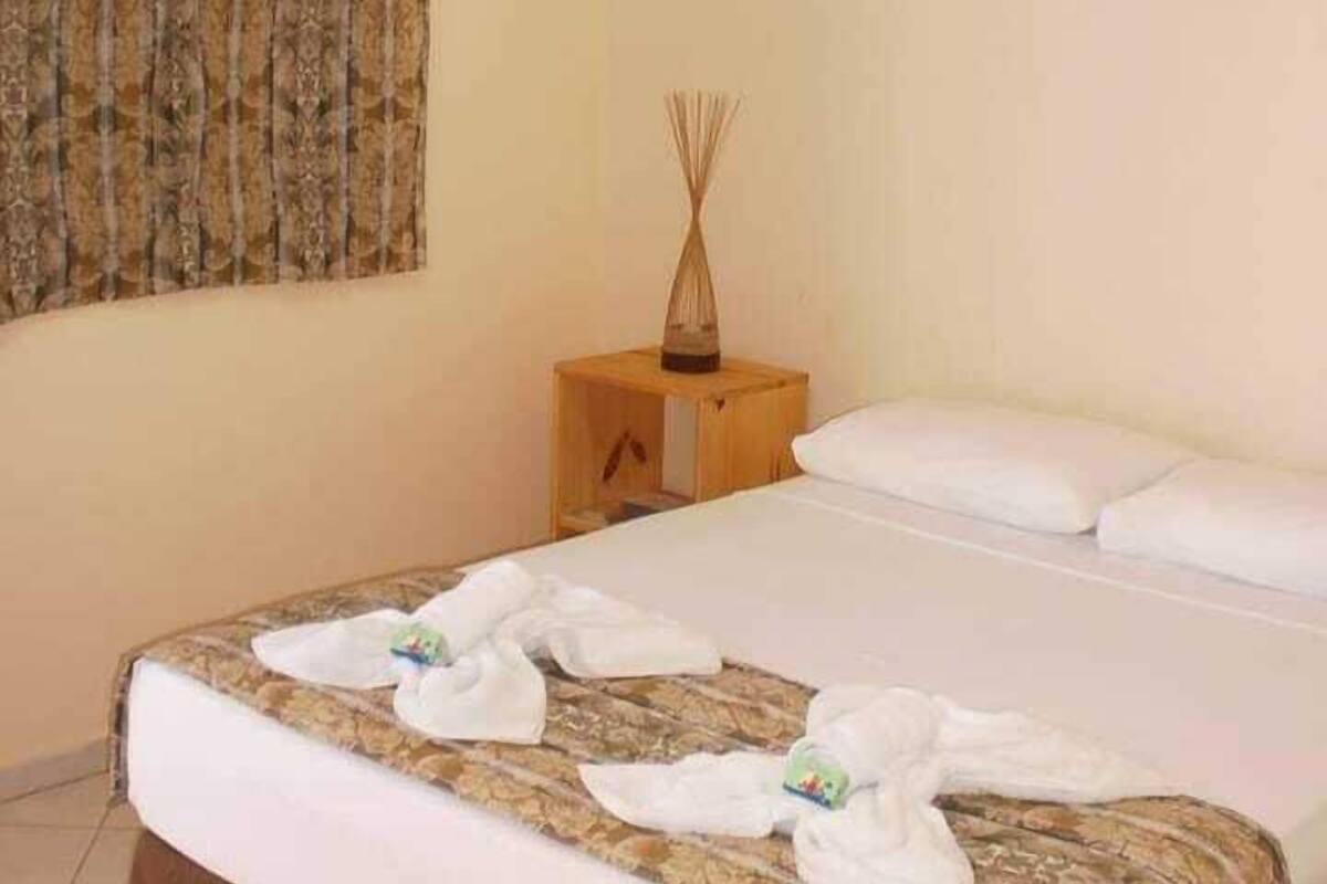 Una camera d'albergo con un letto, tende, un comodino e un condizionatore d'aria.