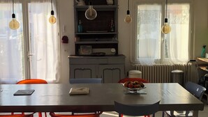 A dining area with a table, chairs, and hanging light bulbs. - Large family home 150 m from the beach, large well-equipped kitchen (Châtelaillon-Plage)