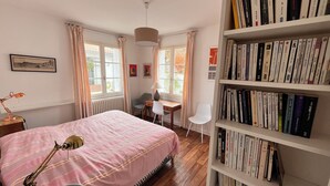 A bedroom with a bed, a desk, a chair, a bookshelf, and a window with curtains. - Large family home 150 m from the beach, large well-equipped kitchen (Châtelaillon-Plage)