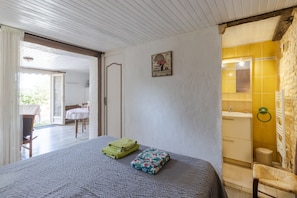Un dormitorio con cama, un baño con baldosas amarillas y un comedor con mesa y sillas.