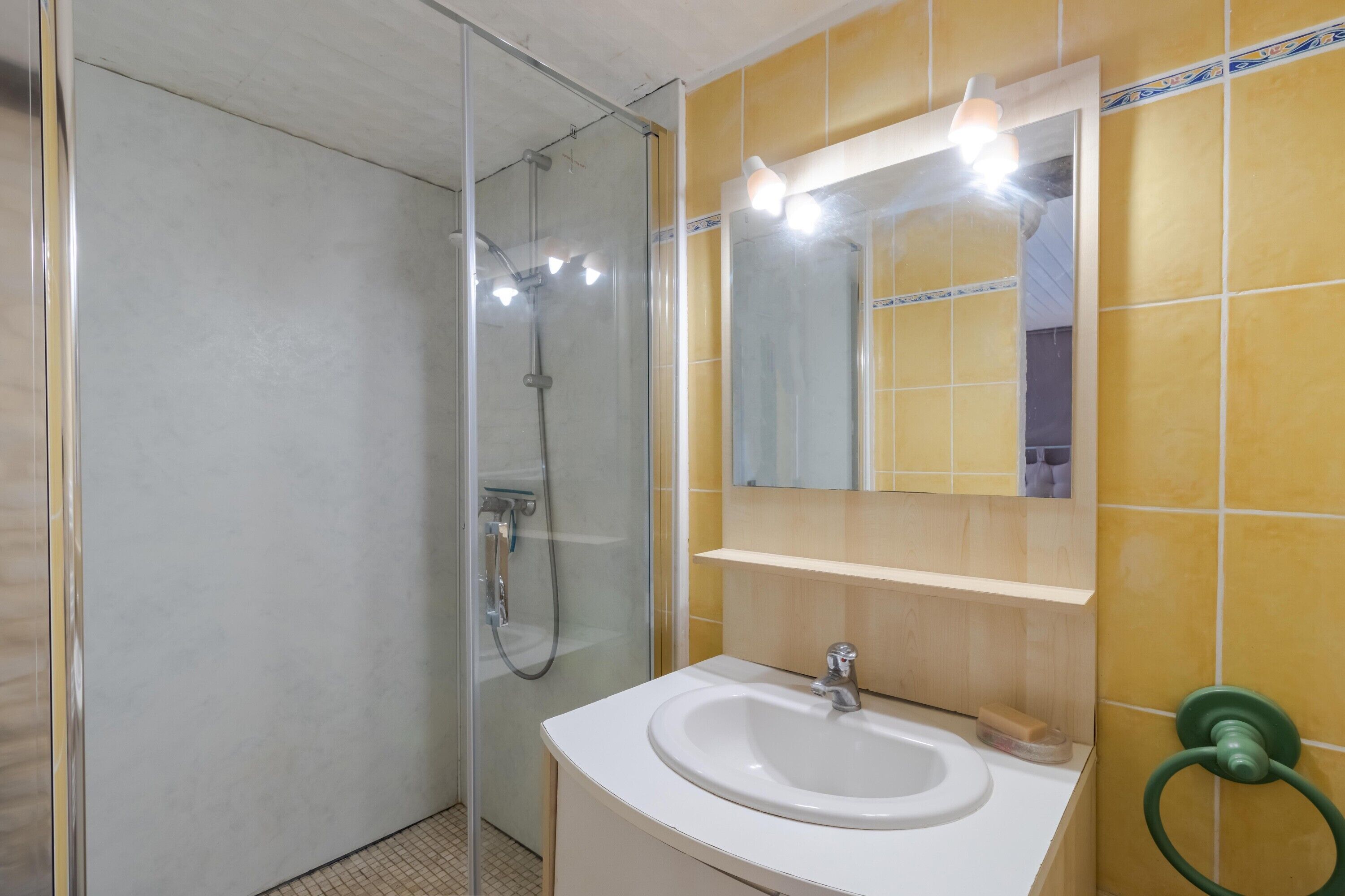 Un baño con ducha de vidrio, un lavamanos blanco y un espejo con iluminación.