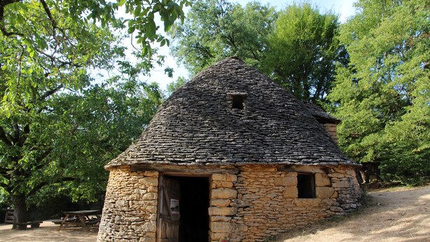 Une petite maison en pierre avec un toit de chaume, une porte en bois et une petite fenêtre.