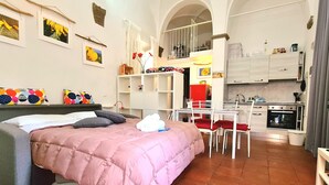 A compact bedroom with a bed, a small kitchenette, and a dining area.