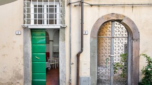 A building with a green door, a window with a metal grill, and a number '1' sign.