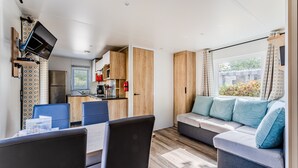 Un espace de vie compact comprenant un coin cuisine, un coin repas et un espace détente avec un canapé et des coussins.