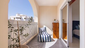Ein Balkon mit einem gestreiften Sitzsack, einem Holzschrank und einem Blumentopf.