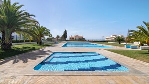 Ein Poolbereich mit mehreren Pools, Palmen und einem Gebäude im Hintergrund.