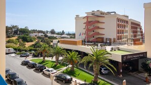 Ein Hotel mit modernem Design, erkennbar an der auffälligen roten und weißen Fassade, einer Dachterrasse und einem Parkplatz mit mehreren Autos.