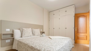 Een slaapkamer met een bed, een kledingkast, een nachtkastje en een deur.