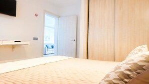 A bedroom with a bed, a wardrobe, a television mounted on the wall, and a door leading to another room. - Apartment Bellissima With Pool and Wi-fi, 200m From the sea in Puerto del Carmen (Tías)