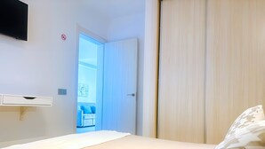 A bedroom with a bed, a wardrobe, a TV mounted on the wall, and a view of a balcony with a blue sofa. - Apartment Bellissima With Pool and Wi-fi, 200m From the sea in Puerto del Carmen (Tías)