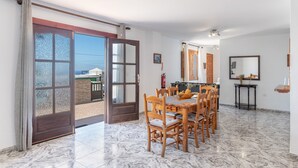 Un comedor con una mesa y sillas, una cocina con mostrador y alacenas, y un gran ventanal que da al exterior.