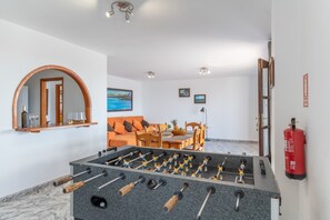 A room with a foosball table, a mirror, a sofa, a dining table with chairs, and a fire extinguisher. - Holiday Apartment 'Andres House' with Sea View, Private Pool and Wi-Fi (Tías)