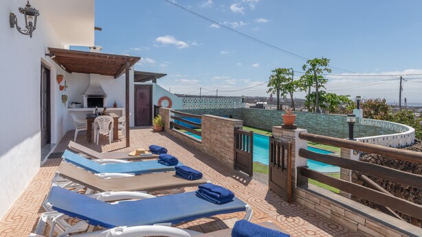 Una terraza en la azotea con sillones de descanso, piscina y vistas a la ciudad.
