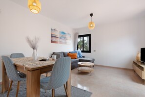 Un salon moderne comprenant un coin repas, un canapé, un téléviseur et des œuvres d’art accrochées au mur.