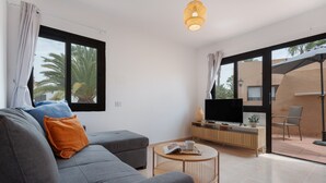 Een moderne woonkamer met een bank, een salontafel en een televisie op een houten dressoir.