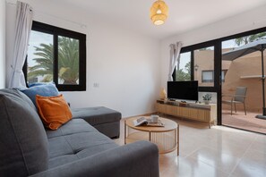 Una sala moderna con un sofá, una mesa de centro y un televisor sobre un mueble de madera.