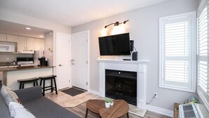 A modern living room with a fireplace, a flat-screen TV mounted above it, a sofa, and a coffee table. - Slopeside Sanctuary (Blue Mountain)