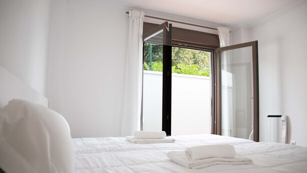A hotel room with a bed, a window with curtains, and a radiator. - APARTAMENTOS TERRAMAR BOIRO With sea views in the Ría de Arousa (Galicia) (Boiro)