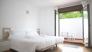 A bedroom with a large bed, a nightstand, a desk with a chair, and a sliding glass door leading to an outdoor area. - APARTAMENTOS TERRAMAR BOIRO With sea views in the Ría de Arousa (Galicia) (Boiro)